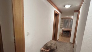 Un pasillo estrecho con un banco de madera, una puerta a la izquierda y un comedor al fondo.