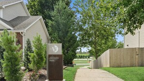 A pathway leading to a building with a sign reading "ASHAWA PARK". - Base Camp – Modern Cozy Retreat with Sauna, Hot Tub & Fun for Families in WDM (West Des Moines)