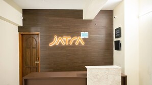 A reception desk with a wooden panel wall and a neon sign above it. - Jatra Flagship Rajshahi City Centre 6 (Rajshahi)