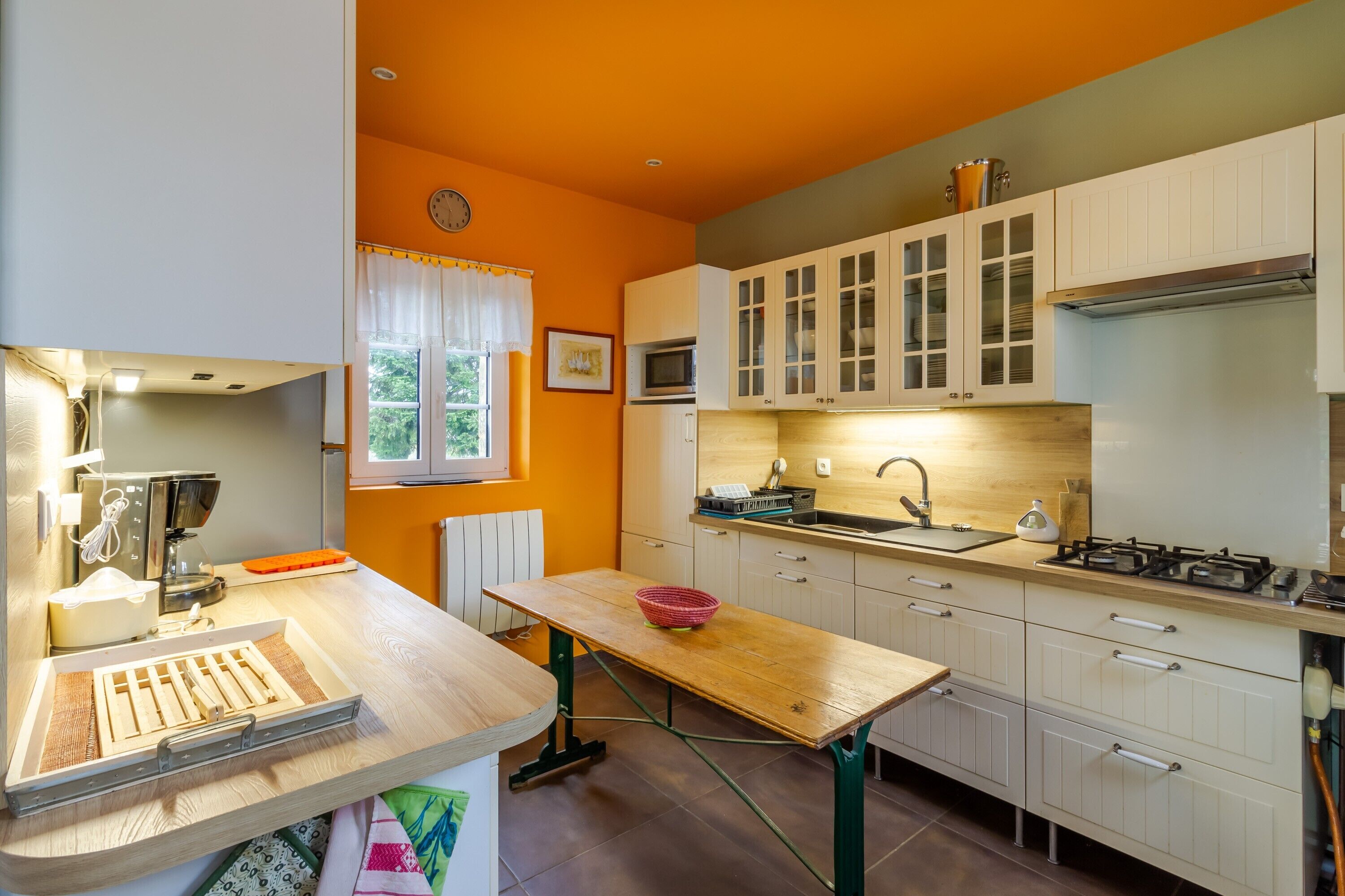 A compact kitchen with white cabinets, a wooden table, a microwave, and a gas stove.