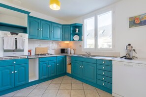 Une cuisine avec des meubles de couleur turquoise, un lave-vaisselle blanc et une fenêtre donnant sur un beau paysage.