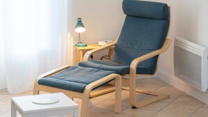 Una habitación moderna con una silla de madera, una mesita y una lámpara.