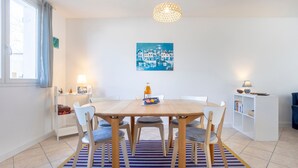 Un comedor con una mesa de madera, sillas, un tapete a rayas, un cuadro en la pared y una estantería.