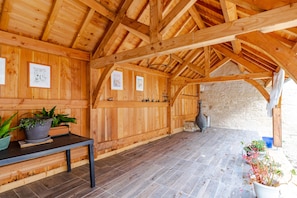 A wooden interior with a tiled floor, a table with potted plants, and framed pictures on the walls.