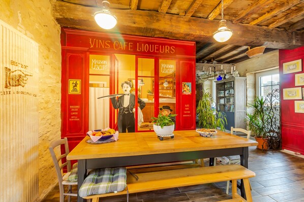 A restaurant interior with a wooden table, chairs, a bench, a red wall, and a ceiling with exposed beams.