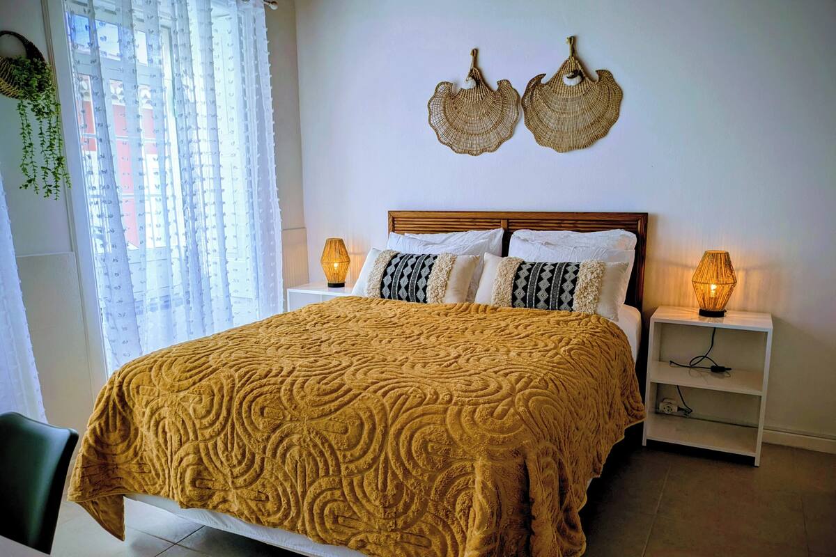 Un dormitorio ordenado con una cama grande, dos lámparas de noche y un adorno en la pared.