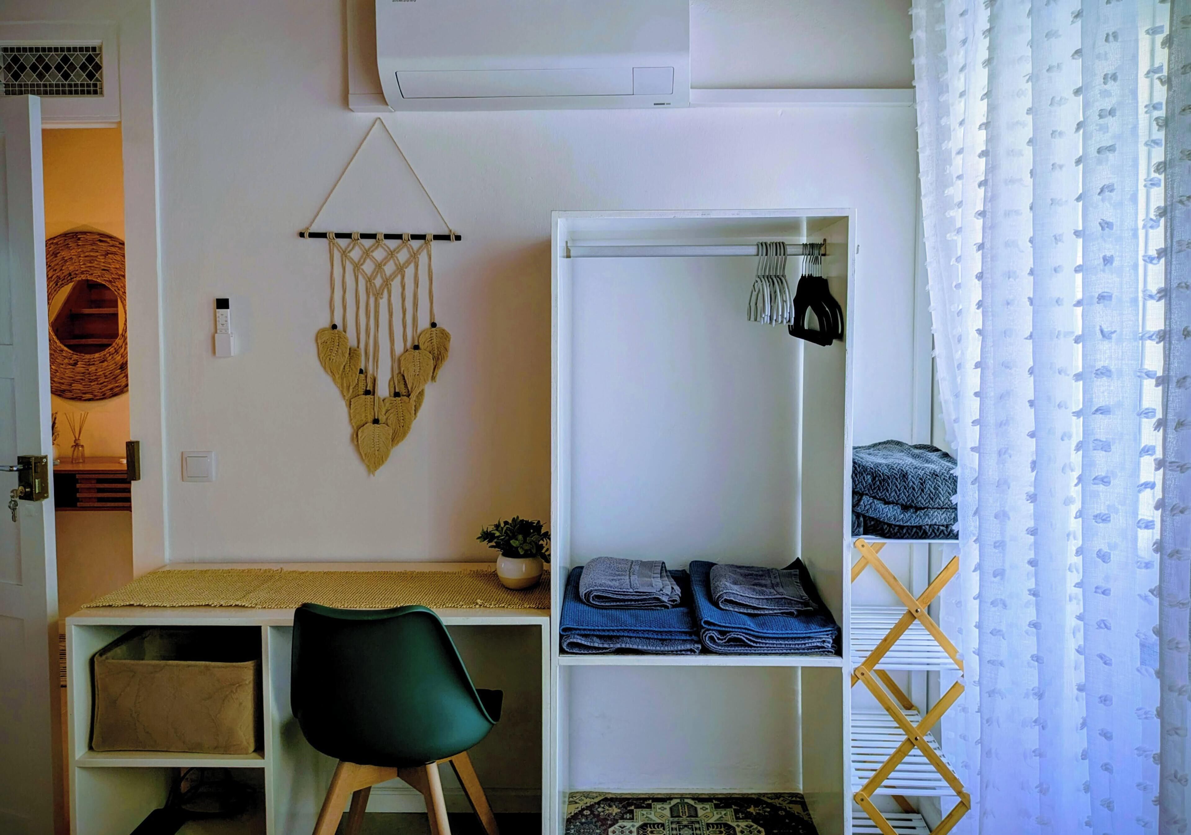 A compact bedroom with a bed, a desk, and a wardrobe.