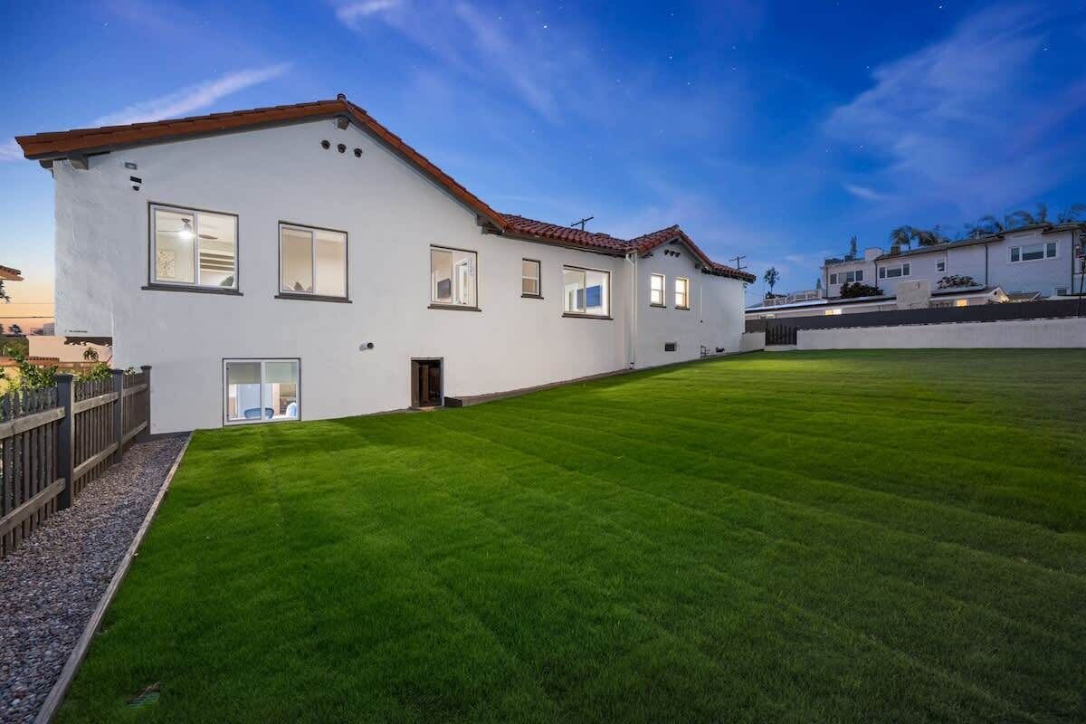 Una moderna casa a due piani con un prato curato e una recinzione in legno.