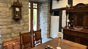 Una cocina rústica con pared de piedra, muebles de madera, un reloj y una araña.