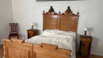 A bedroom with a wooden bed, two nightstands with lamps, a chair, and a wall-mounted air conditioner.