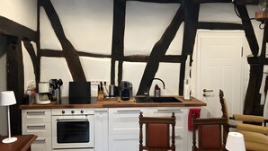 Una cocina con una isla central, armarios blancos, horno empotrado y encimera negra.