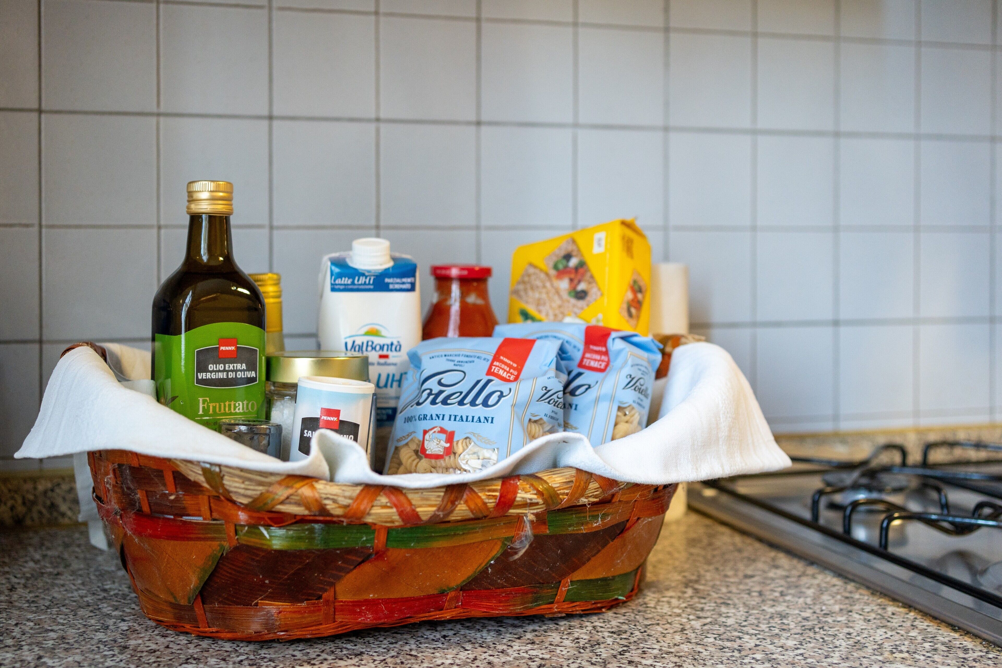 Un piano di lavoro in cucina con un cesto pieno di generi alimentari e bottiglie.