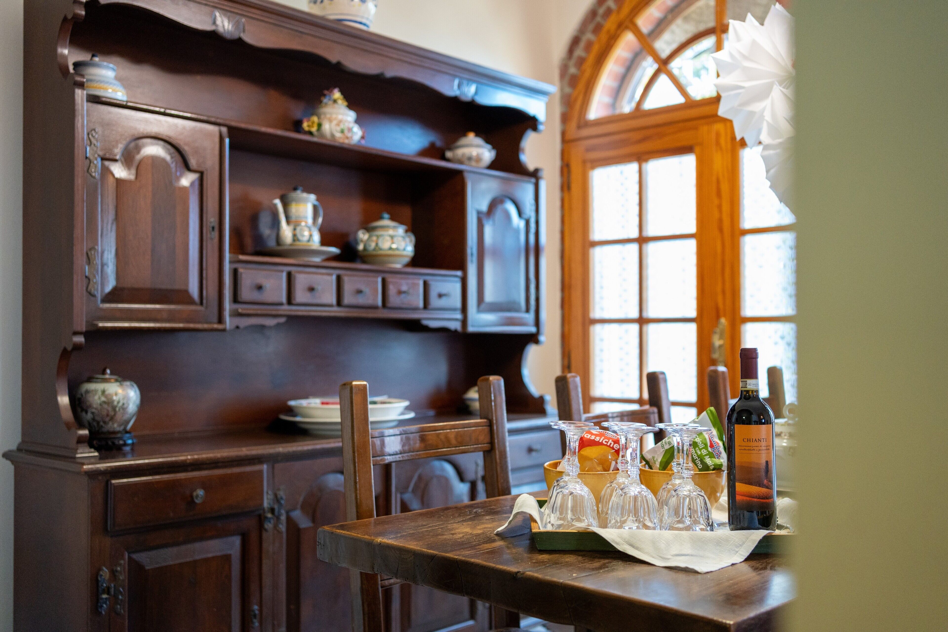 A wooden dining table with a bottle of wine, a bowl, and a pitcher.