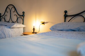 Un lit bien fait, avec une literie à motifs, une table de chevet avec une lampe et un luminaire fixé au mur.