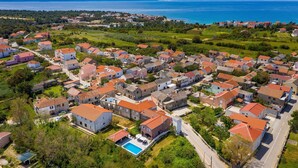 An aerial view of a coastal village with houses, a swimming pool, and a clear view of the sea. - Villa Renata Zadarvillas (Nin)