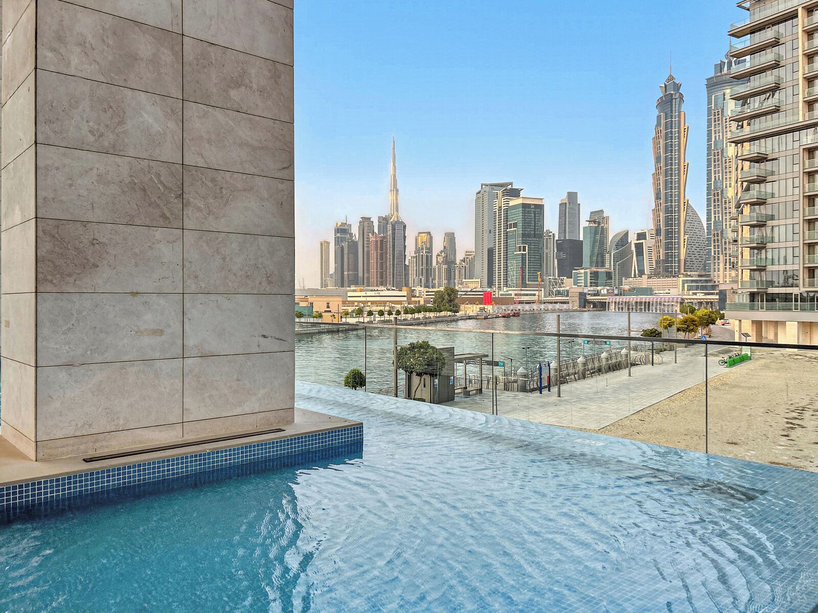 Una piscina con vista a un paisaje urbano, que incluye edificios modernos y un río.