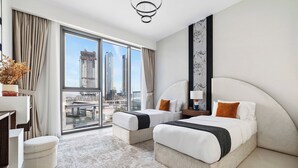 Ett modernt hotellrum med två sängar, ett stort fönster med utsikt över staden, ett skrivbord och en stol.