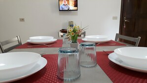 Ein Esstisch mit weißen Tellern, roten Tischsets und klaren Gläsern für Wasser.