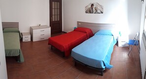 A room with two single beds, a small white dresser, a wooden door, and a wall-mounted artwork. - Trieste Apartment in Marone, BS, Lake Iseo (Marone)