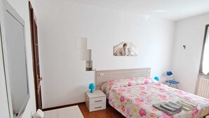 Ein Schlafzimmer mit Bett, Schreibtisch, Stuhl, Nachttisch und einer Wandablage.