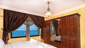 Une chambre d’hôtel avec un grand lit, une armoire et une fenêtre avec des rideaux.