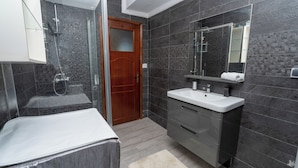 Une salle de bain moderne avec une douche à parois de verre, une porte en bois et un meuble-lavabo avec un miroir.