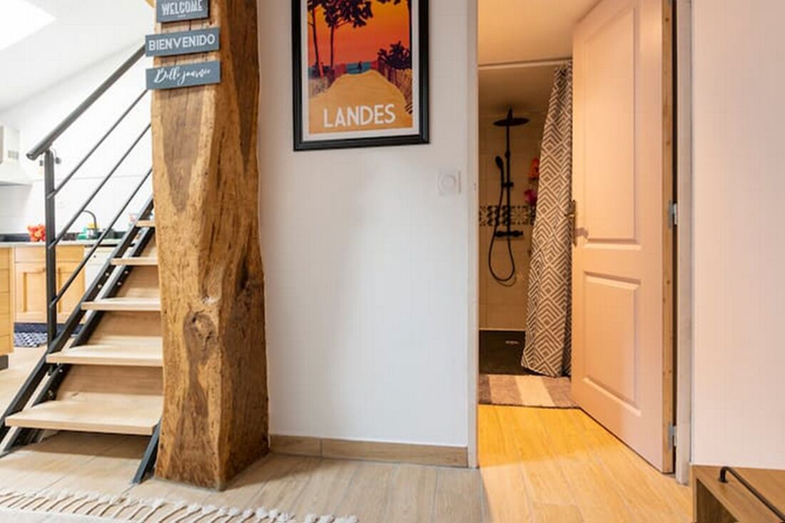 Un escalier agrémenté d’un poteau décoratif en bois, une pancarte de bienvenue et un tableau représentant un paysage au coucher du soleil.