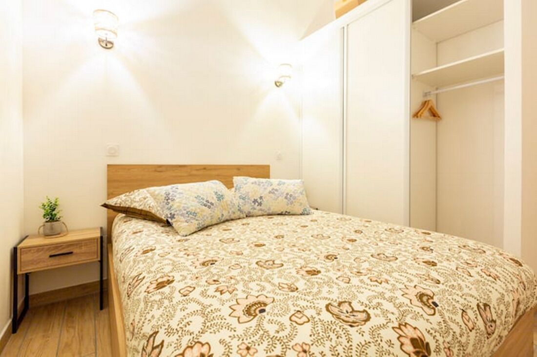Una camera da letto con un letto in legno, biancheria da letto decorata, comodini e un armadio.