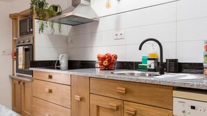 A modern kitchen with wooden cabinets, a built-in oven, a microwave, and a sink.