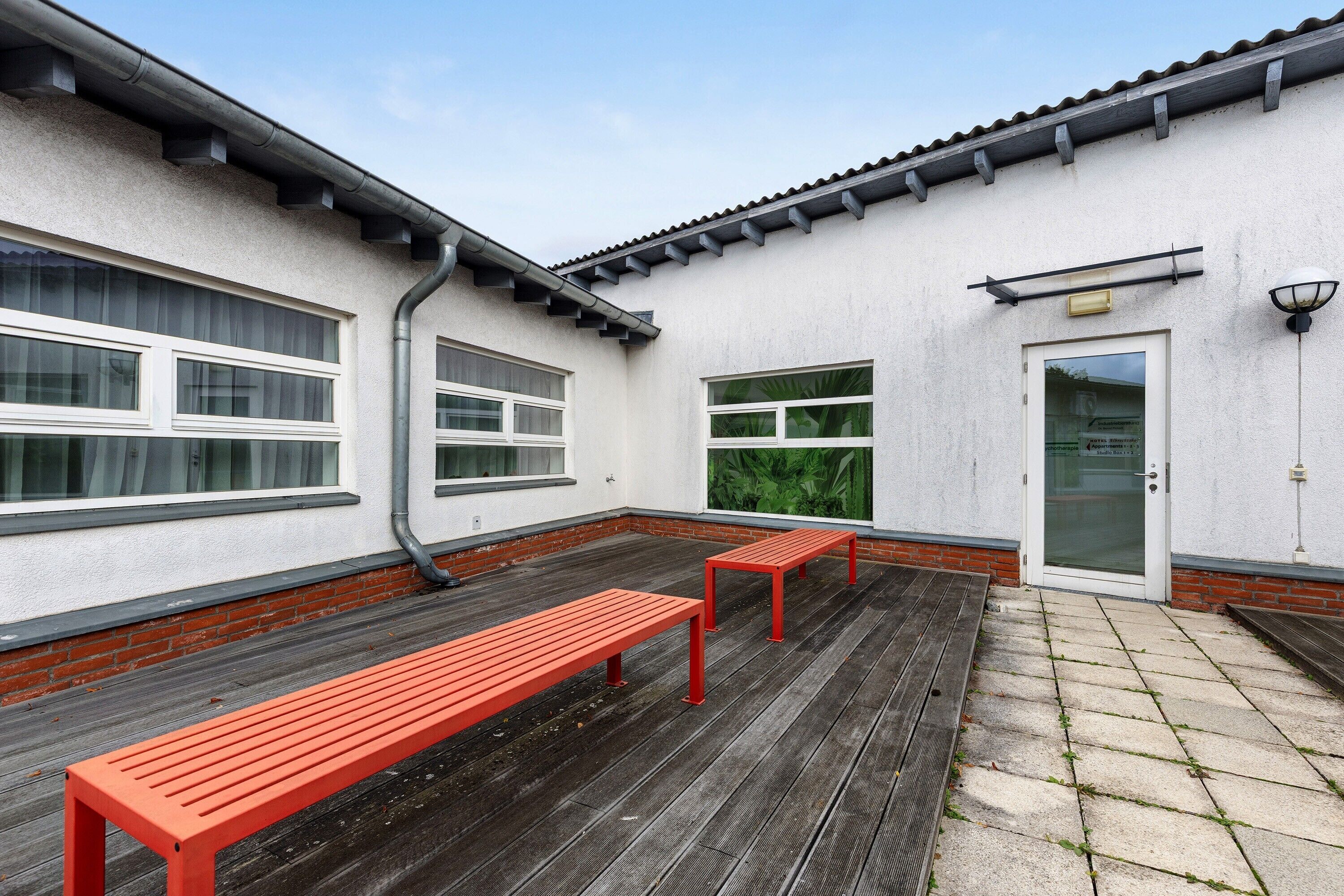 A building exterior with a white facade, a door, and two benches.