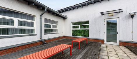 A building exterior with a white facade, a door, and two benches.