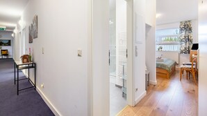 Ein Flur, der zu einem Schlafzimmer mit Bett, Stuhl und Fenster führt.