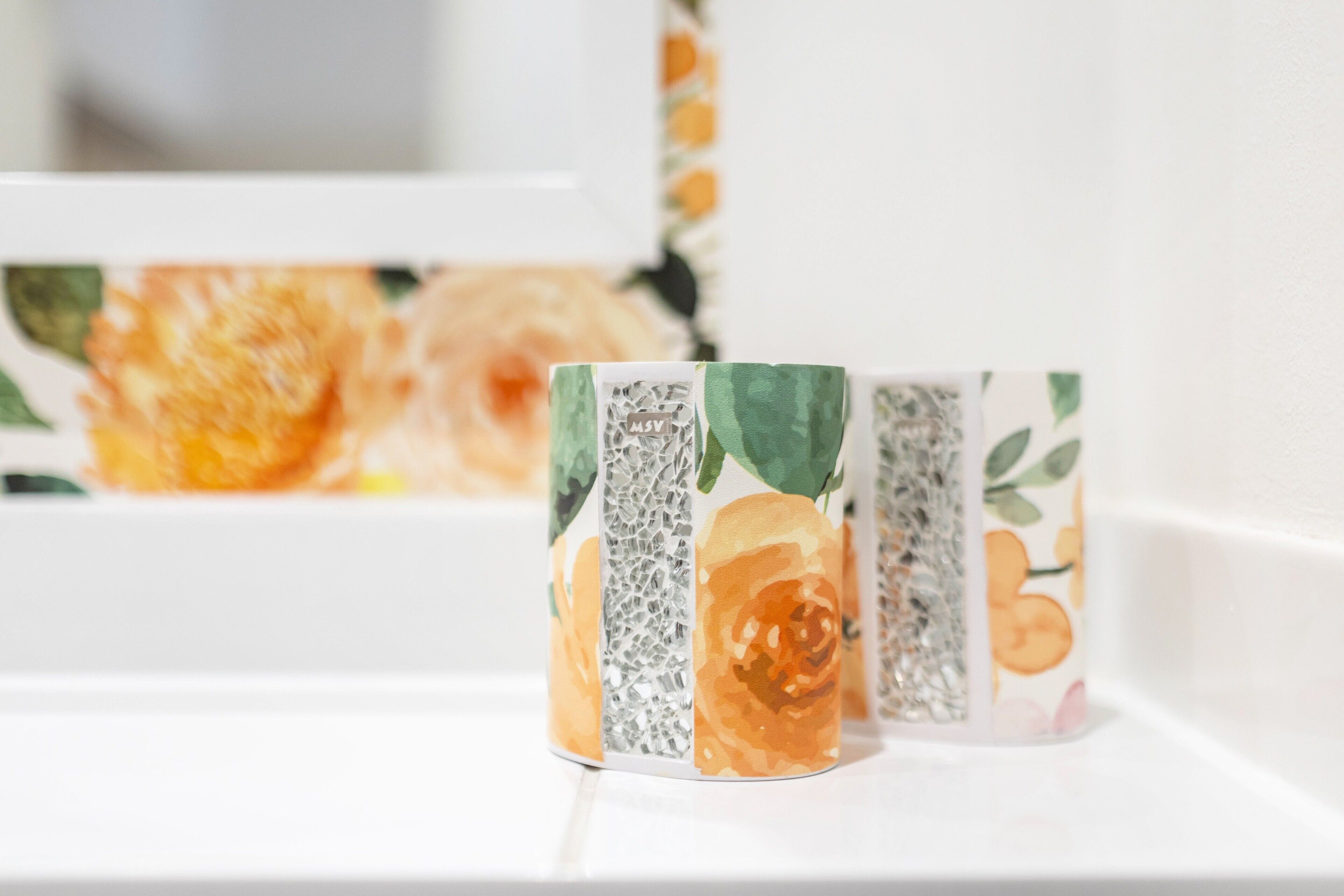 Una serie di oggetti decorativi con motivi floreali su uno scaffale bianco.