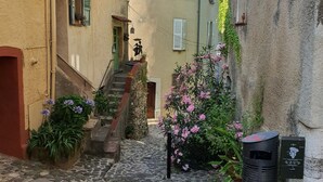 A narrow cobblestone street flanked by buildings with traditional architecture, a staircase, and potted plants. - La Bulle, an authentic and romantic spa (Biot)