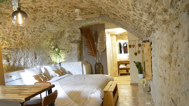 A cozy bedroom with a large bed, wooden furniture, and a stone wall. - La Bulle, an authentic and romantic spa (Biot)