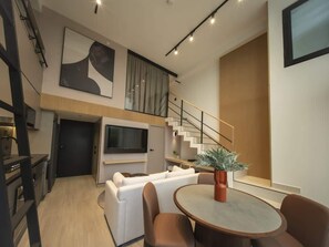 A modern living room with a sofa, a dining table, and a staircase leading to an upper level. - Apartment in Panama with Pool, Gym and WiFi (Ciudad de Panamá)