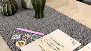 A dining table with a black and white patterned placemat, a vase with flowers, and a menu. - Hostpitaly   La Quiete in Centro (CHIVASSO)