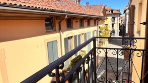 A balcony with a wrought iron railing overlooking a street with terracotta-roofed buildings. - Hostpitaly   La Quiete in Centro (CHIVASSO)