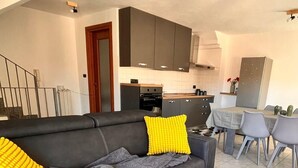A modern living room with a grey sofa, yellow and green patterned rug, and a wooden coffee table. - Hostpitaly   La Quiete in Centro (CHIVASSO)