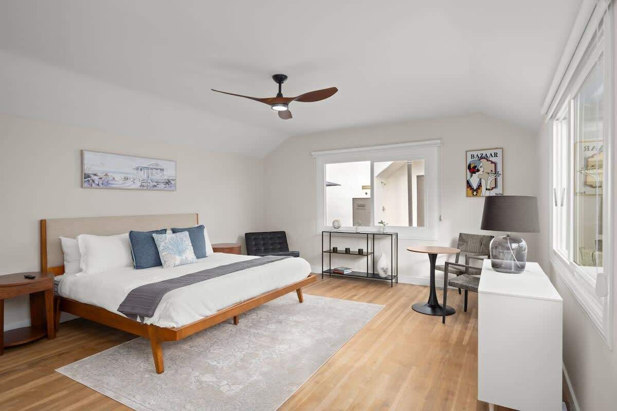 A modern bedroom with a bed, bedside table, and a desk with a chair.