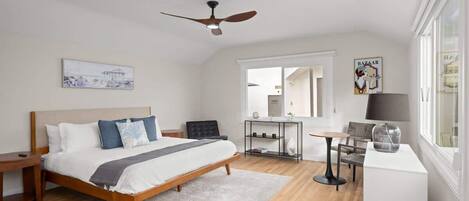 A modern bedroom with a bed, bedside table, and a desk with a chair.