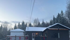 A cabin with a porch, a covered area, and a snow-covered landscape. - Le petit chalet Chertsey (Chertsey)