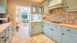 A kitchen with light blue cabinets, a tiled backsplash, and a dining area with natural light. - Host & Stay | Amberleigh (North Sunderland)