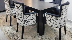 A dining area with a rectangular table and six chairs, a television, and two paintings on the wall. - Golden Mango Heights Apartments (Nairobi)