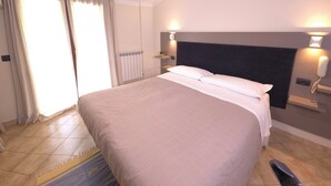 Ein Hotelzimmer mit einem Bett, einem Nachttisch, einem an der Wand befestigten Telefon und einem Heizkörper.