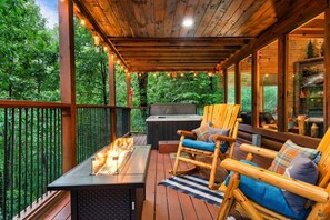 Una terraza de madera con un brasero, asientos exteriores y una parrilla.