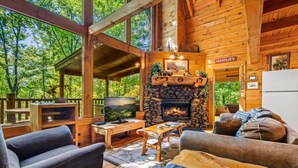 Interior acogedor de una cabaña con chimenea de piedra, muebles de madera y un televisor.