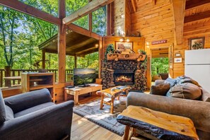 Interior acogedor de una cabaña con chimenea de piedra, muebles de madera y un televisor.
