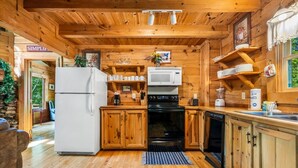 L’intérieur d’une cabane en bois comprend une cuisine équipée d’un réfrigérateur, d’une cuisinière, d’un four à micro-ondes et d’un lave-vaisselle.