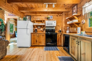 L’intérieur d’une cabane en bois comprend une cuisine équipée d’un réfrigérateur, d’une cuisinière, d’un four à micro-ondes et d’un lave-vaisselle.